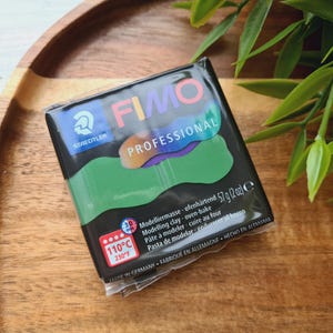 Könnte beinhalten: Eine Packung FIMO Professional Modelliermasse, eine Marke für ofenhärtenden Modellierton. Die Verpackung ist schwarz mit einem Regenbogen an Farben auf der Vorderseite. Die Verpackung trägt die Aufschrift "FIMO Professional" und "110°C 230°F 57g (2 oz)".