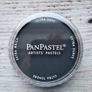 Könnte beinhalten: Ein runder schwarzer PanPastel Künstlerpastell in einem durchsichtigen Plastikbehälter. Der Behälter trägt den Text "PanPastel® Artists' Pastels". Der Behälter trägt auch den Text "Ultra Soft", "Extra Weich", "Ultra Tendre" und "Extra Suave".