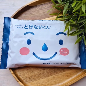 Pode incluir: Embalagem branca com um desenho de rosto de desenho animado, detalhes azuis e texto japonês. A embalagem apresenta um rosto sorridente com olhos azuis, uma lágrima e uma bochecha rosa. O texto diz "Argila leve à prova d'água".