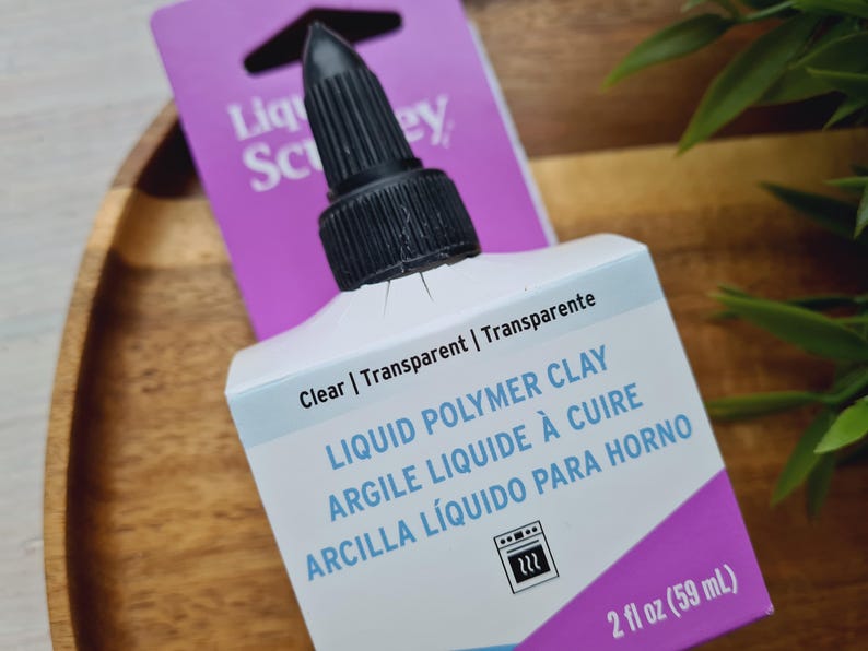 May include: A 2-ounce bottle of clear liquid polymer clay. The bottle has a black cap and a label that says "Liquid Polymer Clay, Argile Liquide &agrave; Cuire, Arcilla L&iacute;quido Para Horno".