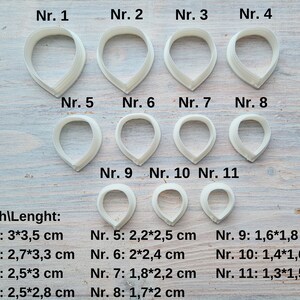 Może przedstawiać: Jedenastu białych plastikowych wycinarek do płatk&oacute;w kwiat&oacute;w w r&oacute;żnych rozmiarach, oznaczonych numerami od 1 do 11. Każda wycinarka jest pokazana z podanymi wymiarami szerokości i długości w centymetrach.