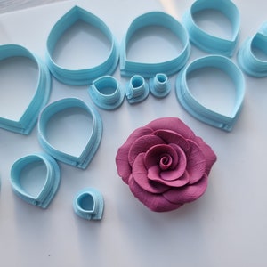 Może przedstawiać: Zestaw niebieskich plastikowych wykrawaczy do kwiat&oacute;w z r&oacute;żową r&oacute;żą z lukru w środku.
