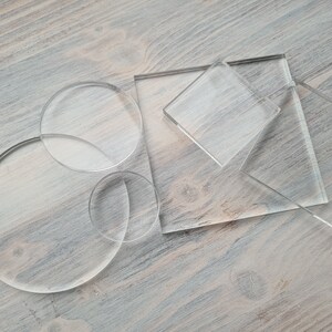 May include: A set of clear acrylic circles and squares of various sizes. The acrylic pieces are arranged on a light brown wooden surface.