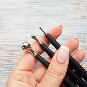 Puede incluir: Tres herramientas con mango negro y diferentes puntas met&aacute;licas para nail art. Las puntas incluyen una bola redonda, una punta puntiaguda y una punta ligeramente redondeada.
