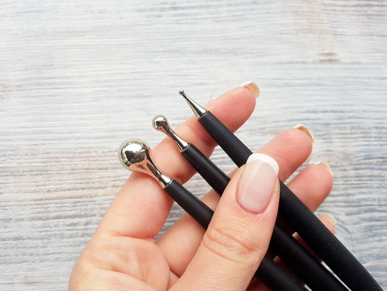 Puede incluir: Tres herramientas con mango negro y diferentes puntas met&aacute;licas para nail art. Las puntas incluyen una bola redonda, una punta puntiaguda y una punta ligeramente redondeada.