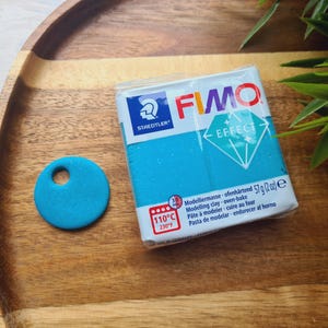 May include: A package of turquoise blue FIMO Effect modeling clay. The package has a diamond shape with the text "FIMO EFFECT" on it. The package also includes the text "STAEDTLER" and "Modellermasse - ofenhärtend 57g (2 oz) e".
