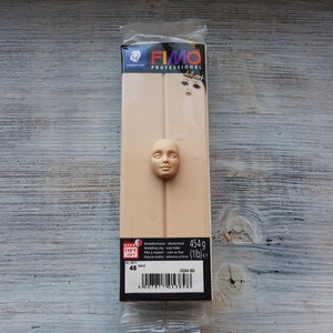 Puede incluir: Un paquete de arcilla para modelar FIMO Professional doll art de color marrón claro. El paquete muestra una cara esculpida en la arcilla. El paquete está etiquetado con el nombre de la marca FIMO y el peso 454g (1lb).