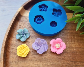 May include: A blue silicone mold with six flower shapes, and five finished sugar flowers in various colors, including yellow, pink, purple, and blue.