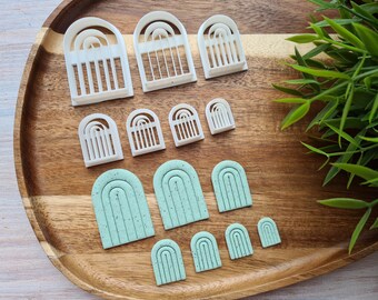 May include: A set of 10 white and green plastic arch cookie cutters. The cutters are in various sizes and feature a rounded arch shape with multiple lines.