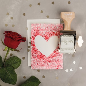 Puede incluir: Una tarjeta de San Valent&iacute;n roja y blanca con una forma de coraz&oacute;n en el centro. La tarjeta est&aacute; rodeada de un patr&oacute;n de corazones rojos y las palabras "Te amo". Tambi&eacute;n se ve un sello de goma de estilo vintage con las palabras "trodat vintage" en la imagen.