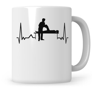 May include: White ceramic mug with a black silhouette of a physiotherapist helping a patient, and a heartbeat line design. The mug has a curved handle and is suitable for hot or cold drinks.