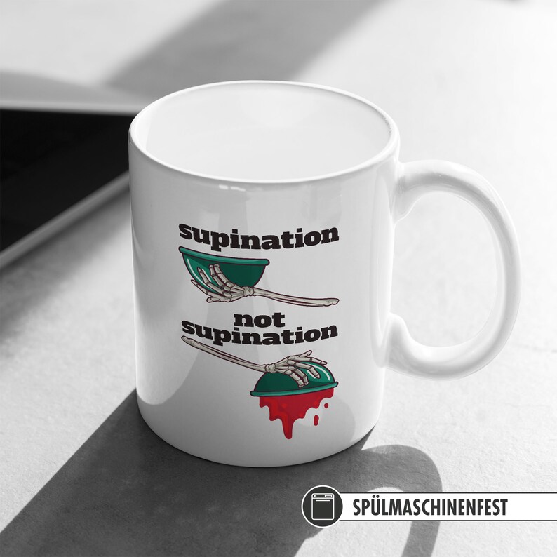 May include: White ceramic coffee mug with a black and green illustration of a skeleton hand holding a bowl. The text "supination" and "not supination" is printed on the mug.