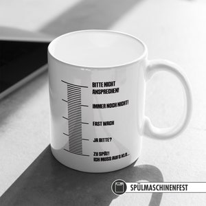 May include: White ceramic mug with black text that reads "Bitte nicht ansprechen! Immer noch nicht! Fast wach Ja bitte? Zu sp&auml;t! Ich muss aufs Klo..." and a dishwasher safe symbol with the text "Sp&uuml;lmaschinenfest".