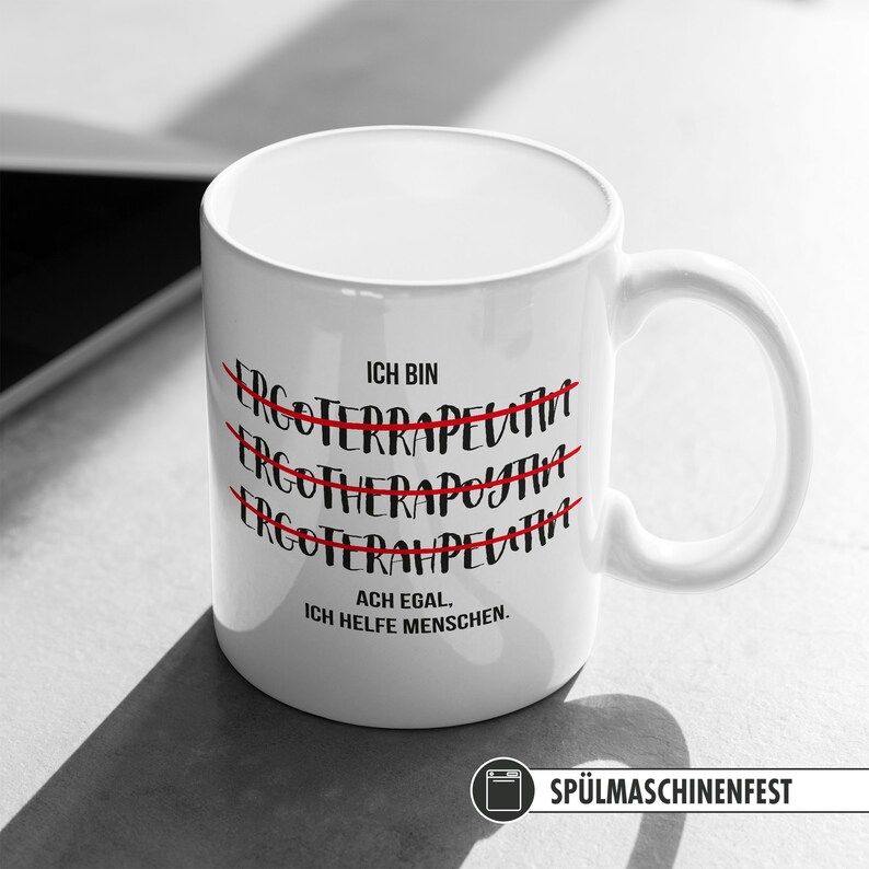 May include: White ceramic mug with black text that reads "Ich bin Ergotherapeutin. Ach egal, ich helfe Menschen."  The text "Ergotherapeutin" is crossed out three times with a red line. The mug is dishwasher safe.