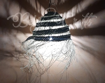 May include: A woven pendant light fixture with a black and white striped design. The light fixture is made of natural materials and has a fringed edge.