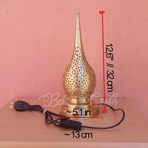 Puede incluir: L&aacute;mpara de mesa de metal dorado con un dise&ntilde;o decorativo perforado. La l&aacute;mpara mide 32 cm de alto y tiene una base de 13 cm de di&aacute;metro. La l&aacute;mpara tiene un cable con un interruptor de encendido/apagado.