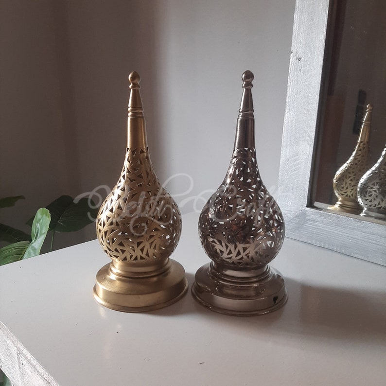May include: Two decorative candle holders with intricate cut-out designs. One is gold and the other is silver.