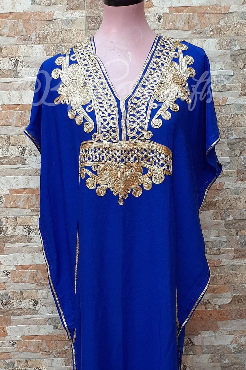 May include: A royal blue kaftan with gold embroidery. The embroidery features intricate patterns and designs around the neckline and shoulders.