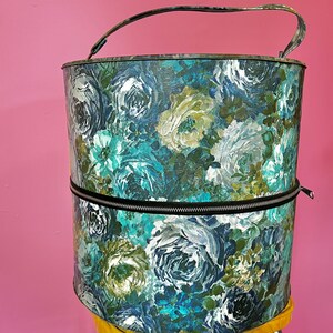 May include: A vintage hat box with a floral pattern in shades of blue, green, and white. The box has a zipper closure and a handle.