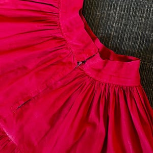 May include: A bright pink skirt with a gathered waist and a zipper closure in the back.