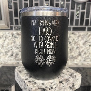 May include: Black stainless steel wine tumbler with the text "I'm trying very hard not to connect with people right now" and two stylized roses.