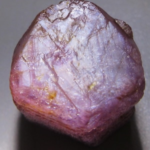 Puede incluir: Una gran gema de rubí púrpura facetada con un acabado natural y rugoso.