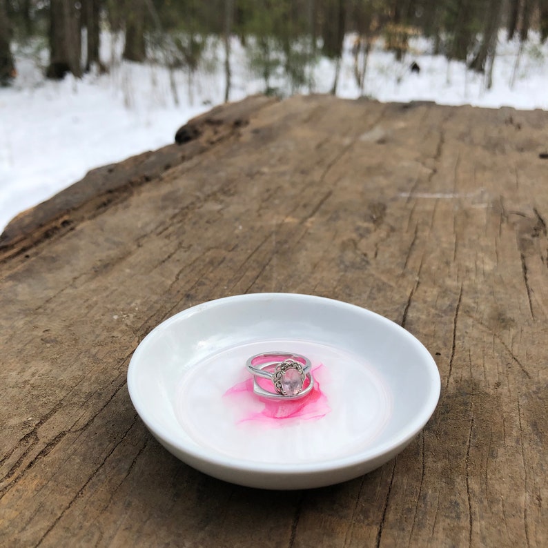 White ceramic jewelry dish with a pink metallic alcohol ink design