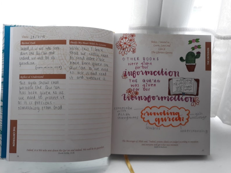 May include: Open notebook with handwritten notes and illustrations. The text includes the date, reflections, and key phrases like "Purify My Heart With Its Lessons" and "Receiving Quran." The notebook has a blue and white patterned cover.