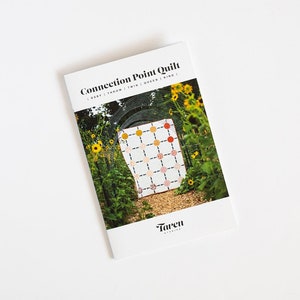 May include: A white booklet with the title "Connection Point Quilt" and a photo of a quilt with a geometric pattern of circles in shades of red, orange, and yellow. The quilt is displayed in a garden setting with sunflowers.