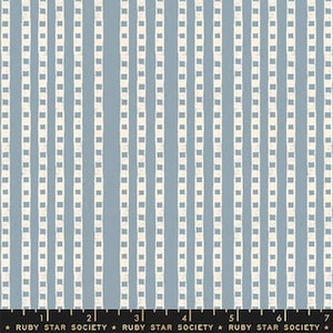 May include: A fabric swatch featuring a dusty blue background with vertical stripes composed of white, hand-drawn, dashed lines. A black ruler at the bottom shows measurements in inches, with the text Ruby Star Society printed repeatedly.