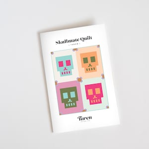 May include: A quilt pattern featuring four colorful pixelated skulls with pink, green, blue, and orange accents. The pattern is titled "Skullmate Quilt - Throw".