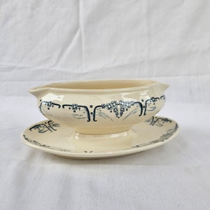 May include: A white ceramic gravy boat with a blue and white geometric design. The boat has a matching saucer.