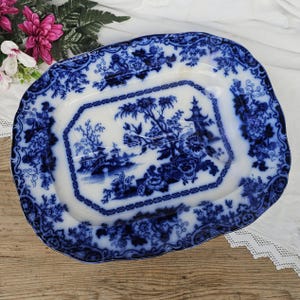 Peut inclure: Un plat de service ancien en porcelaine bleue et blanche. Le plat présente une scène de paysage centrale avec une pagode et une bordure florale. Les bords ont un design festonné. Le design général est un motif de transfert bleu et blanc classique.