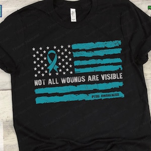 May include: A black t-shirt with a distressed American flag design in teal blue. The flag has a teal blue ribbon in the top left corner and the text "NOT ALL WOUNDS ARE VISIBLE" in white. The text "PTSD AWARENESS" is in white below the flag.