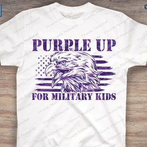 Puede incluir: Dise&ntilde;o de camiseta Purple Up for Military Kids con una bandera estadounidense de camuflaje morado con un &aacute;guila calva en el centro.