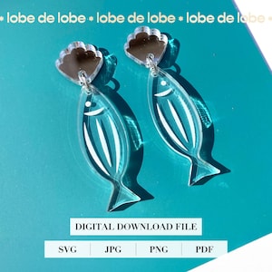 Könnte beinhalten: Ein Paar transparente Acryl-Ohrringe mit einem Fischdesign und einem Muschel-Anhänger. Die Ohrringe befinden sich auf einem türkisfarbenen Hintergrund.