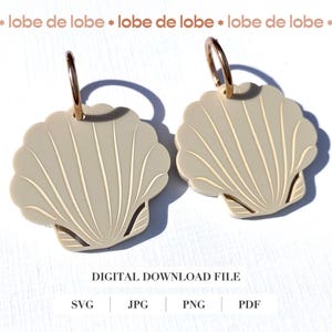 Puede incluir: Un par de pendientes de concha de mar de color crema con aros dorados. Las conchas tienen un diseño texturizado y son un accesorio de verano popular.