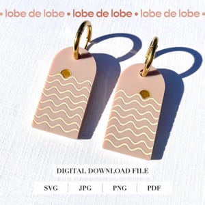 Puede incluir: Un par de pendientes color rubor con aros dorados. Cada pendiente presenta una forma rectangular con la parte superior redondeada, adornada con un diseño de líneas onduladas y un gráfico de sol. El texto "DIGITAL DOWNLOAD FILE" es visible.