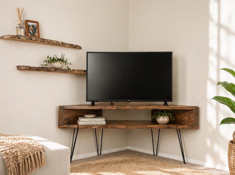 May include: A rustic, corner TV stand made of dark wood with black hairpin legs. The stand features open shelving and a flat-screen TV. Two matching floating shelves are above the stand, along with a framed photo and small plants.