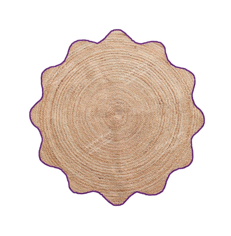May include: A round, natural-toned jute rug with a scalloped edge. The rug's border is a deep purple, creating a contrast with the neutral tones of the woven jute. The rug has a circular pattern.