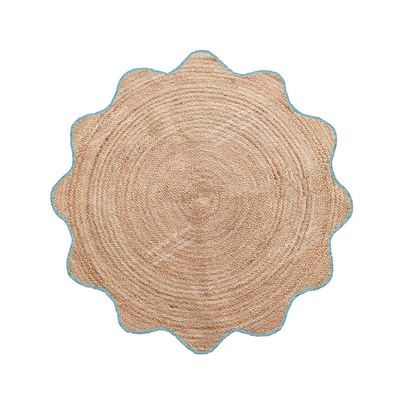 May include: A round jute rug with a scalloped edge. The rug is a natural tan color with a light blue border. The rug has a woven texture and is suitable for indoor use.