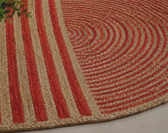 Könnte beinhalten: Ein runder geflochtener Teppich in den Farben Naturbeige und leuchtendem Orange. Das Design umfasst einen Bereich mit vertikalen Streifen auf der linken Seite und einen Bereich mit konzentrischen Kreismustern auf der rechten Seite aus Fasern.