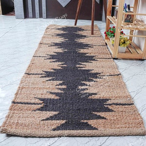 May include: A natural fiber rug with a geometric pattern in black and tan. The rug is made of jute and has a woven texture.