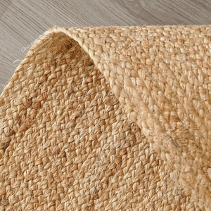 "Showcasing a timeless aesthetic, this hand-braided mat utilizes the natural golden hues of jute for a light, airy feel. The solid color and pronounced vertical texture make it effortlessly adaptable to various styles, including Coastal, Scandinavian, or Modern Farmhouse."