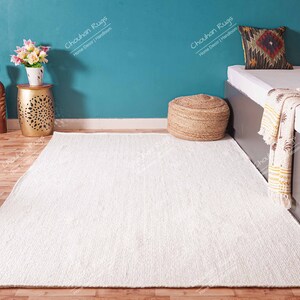 "Captured from above on a crisp white background, this durable rectangular area rug showcases the rustic beauty of undyed natural jute. The meticulous braided construction is visible through the slight variations in fiber and tone, emphasizing its authentic, artisan-made quality and soft, neutral aesthetic."