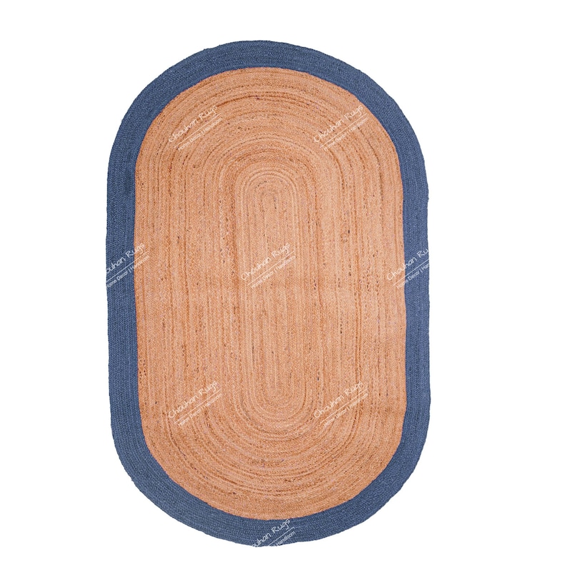 K&ouml;nnte beinhalten: Ein ovaler Teppich aus Naturfasern mit einem blauen Rand. Der Teppich ist aus Jute und hat eine gewebte Struktur.