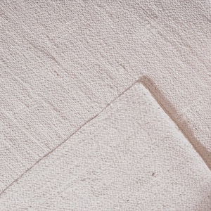 "This image features a solid, unadorned mat focusing entirely on the material's integrity. The hand-braiding technique gives the rug a subtle, inherent striping texture, allowing the natural color and slight imperfections of the jute to take center stage. A timeless, versatile piece that complements any color palette."