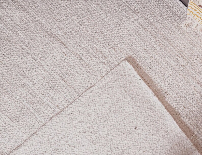 "This image features a solid, unadorned mat focusing entirely on the material's integrity. The hand-braiding technique gives the rug a subtle, inherent striping texture, allowing the natural color and slight imperfections of the jute to take center stage. A timeless, versatile piece that complements any color palette."