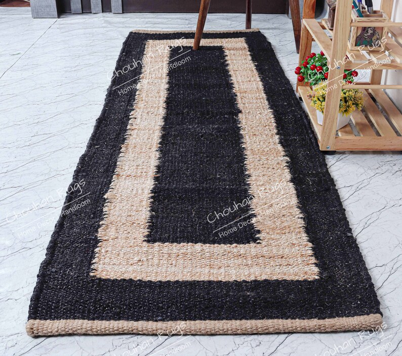 May include: A black and natural jute rug with a border. The rug has a rectangular shape and is made of natural fibers.