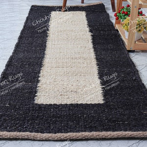 May include: A black and white jute rug with a rectangular white center and a black border. The rug has a fringe border.